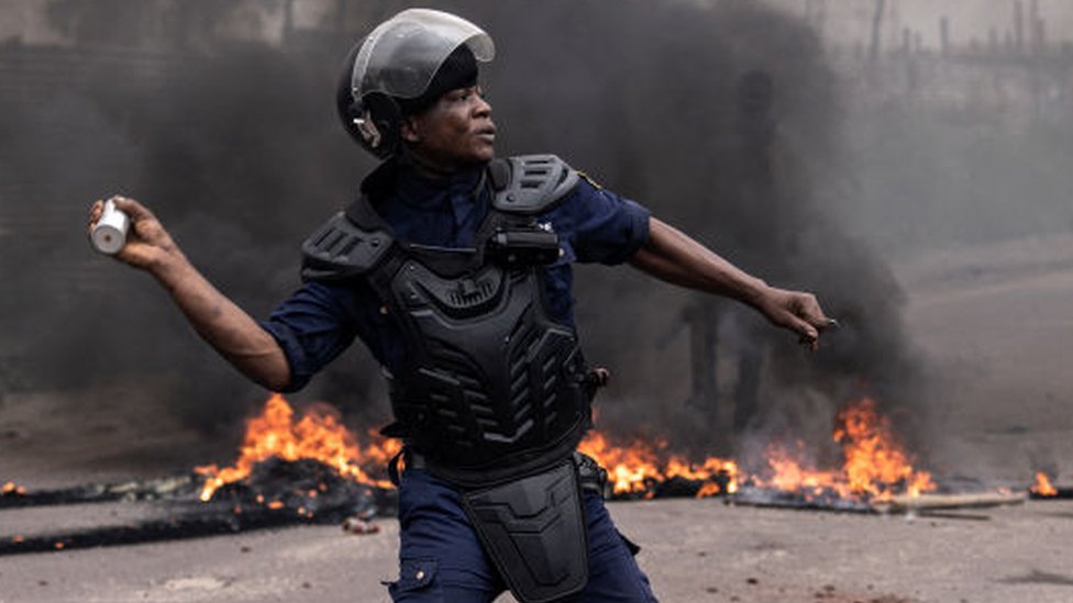 A Police officer throws a flash bang grenade during an opposition demonstration in Kinshasa on December 27, 2023